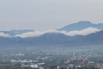 Aerial view of townscape and mountains against sky