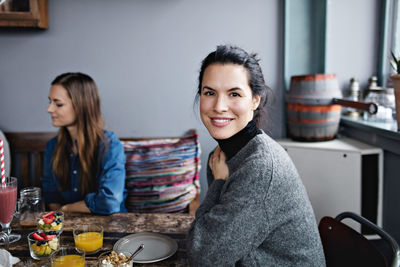 Portrait of smiling woman having brunch with friend at table