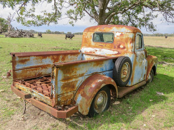 Abandoned vintage car on field against sky