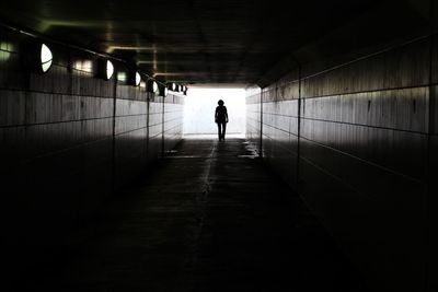 Rear view of person walking in tunnel