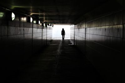 Rear view of people walking in tunnel