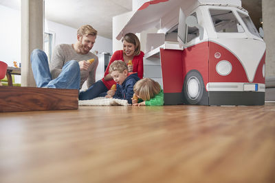 Happy family with popsicles and model car in living room