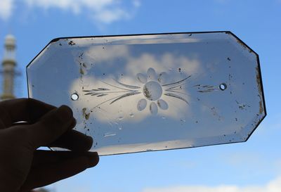Close-up of hand holding glass against sky