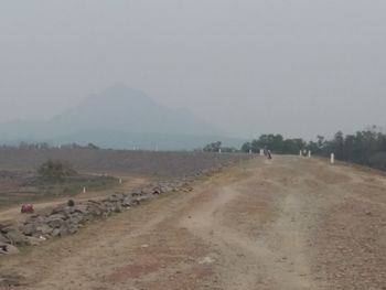 Dirt road on field against sky