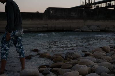 Rear view of man at beach against sky