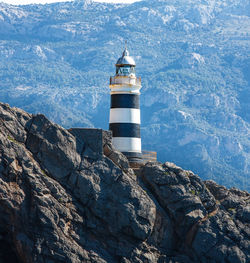 Lighthouse by sea against mountain