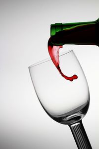 Close-up of red wine bottle against white background