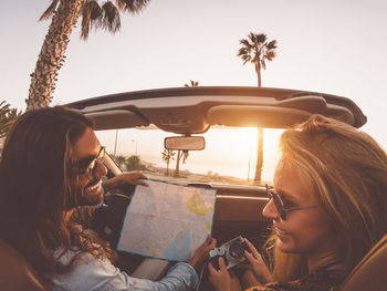 Man and woman sitting in car against sky