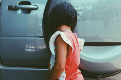 Side view of girl standing by car