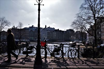 Silhouette of city by river against sky