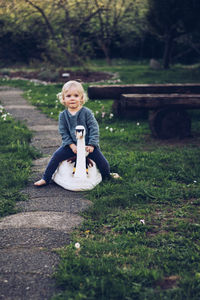 Portrait of baby girl sitting on toy on footpath