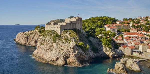 Buildings by sea against sky