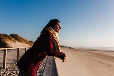 Young woman with eyes closed relaxing at beach at sunset. holidays and relaxation concept