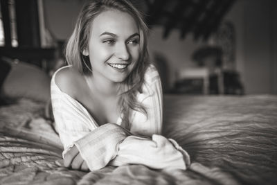 Portrait of smiling young woman lying on bed