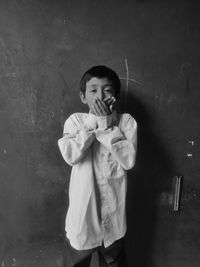 Portrait of little boy standing against wall