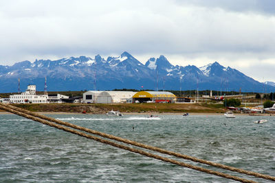 Scenic view of sea by snowcapped mountains against sky