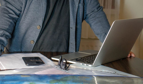 Midsection of man using laptop at table