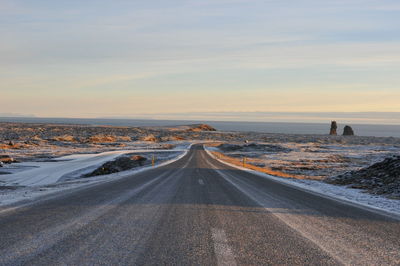 Road amidst land against sky during sunset