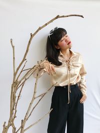 Young woman looking away while standing against plants