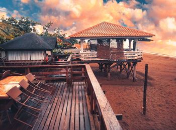 Gazebo by building against sky during sunset