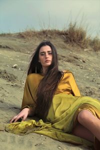 Portrait of young woman sitting on sand