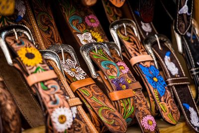 Cowboy boots and leather belts in a saddlery, footwear and accessories business showcase.