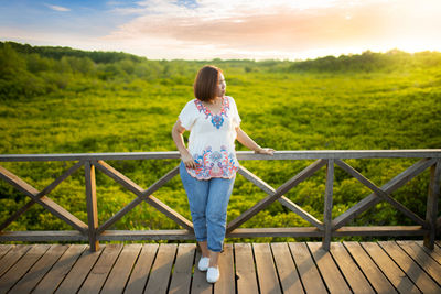 Rear view of woman standing on railing against sky