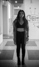 Portrait of young woman standing against wall