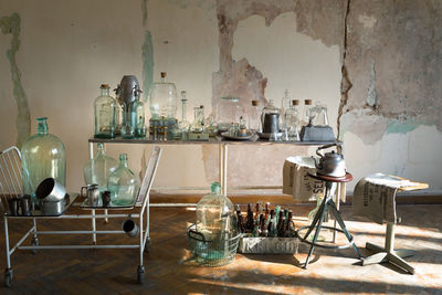 Empty chairs and table with glassware against wall at home