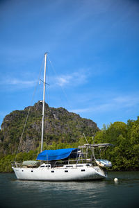 Sailboats moored on sea against blue sky