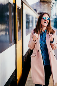 Young woman wearing sunglasses standing by train