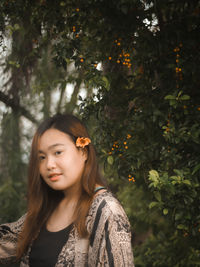 Portrait of a beautiful young woman standing against plants