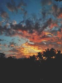 Silhouette of trees against cloudy sky