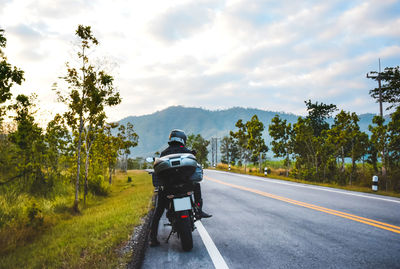 Person riding motorcycle on road against sky