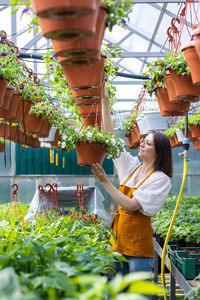 Woman standing by potted plants in greenhouse