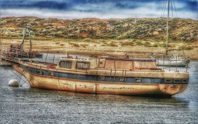 Abandoned boat in river against sky