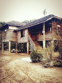 Exterior of abandoned house in front of farm against sky