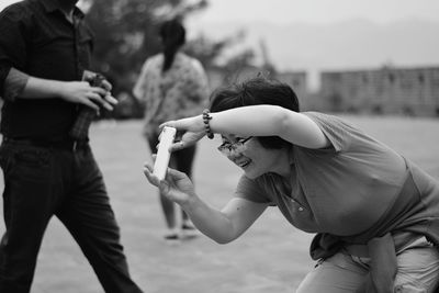 Smiling woman photographing with smart phone while standing outdoors