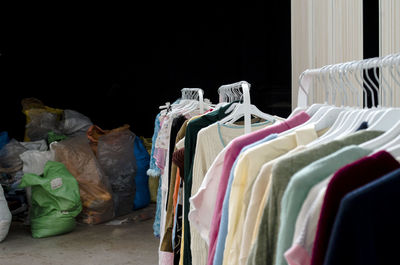 Rolling rack with hanging clothes and bags full of preowned garments in a vintage market
