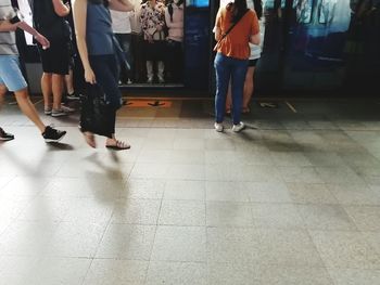 Low section of people walking on tiled floor