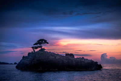 Rock formation in sea against cloudy sky during sunset at raja ampat islands