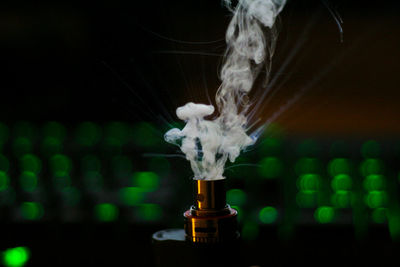 Close-up of electronic cigarettes against green defocused lights against black background
