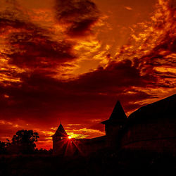 Silhouette of built structure against cloudy sky at sunset