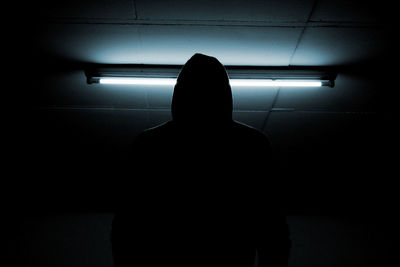 Rear view of silhouette man standing against illuminated wall