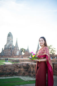 Portrait of woman standing in traditional clothing against temple