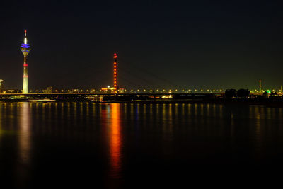 Tv tower reflecting on rhine river at night in düsseldorf, germany