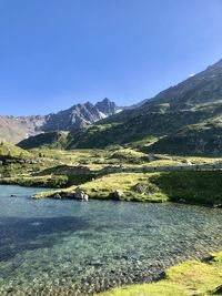 Scenic view of lake and mountains against clear blue sky