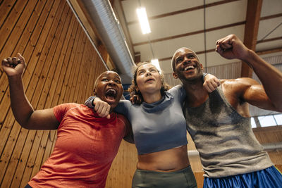 Low angle view of male and female athletes cheering together at sports court