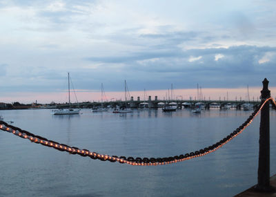 Sailboats moored in river against sky