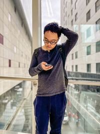 Portrait of young woman standing against building